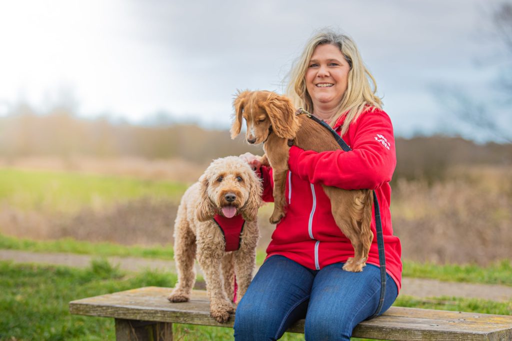 Charlotte from We Love Pets Stevenage hold a dog with one next to her