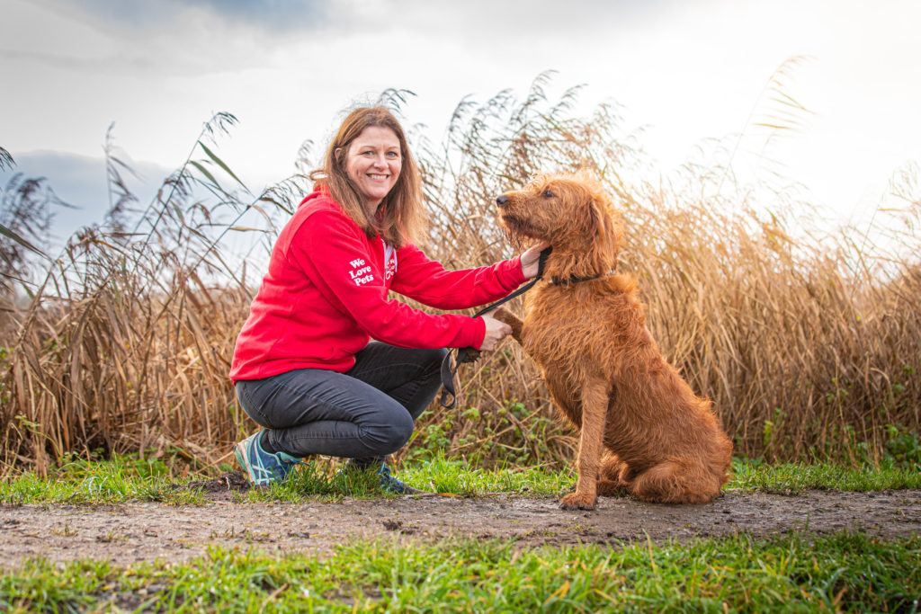 Woman crouching down shaking dogs paw