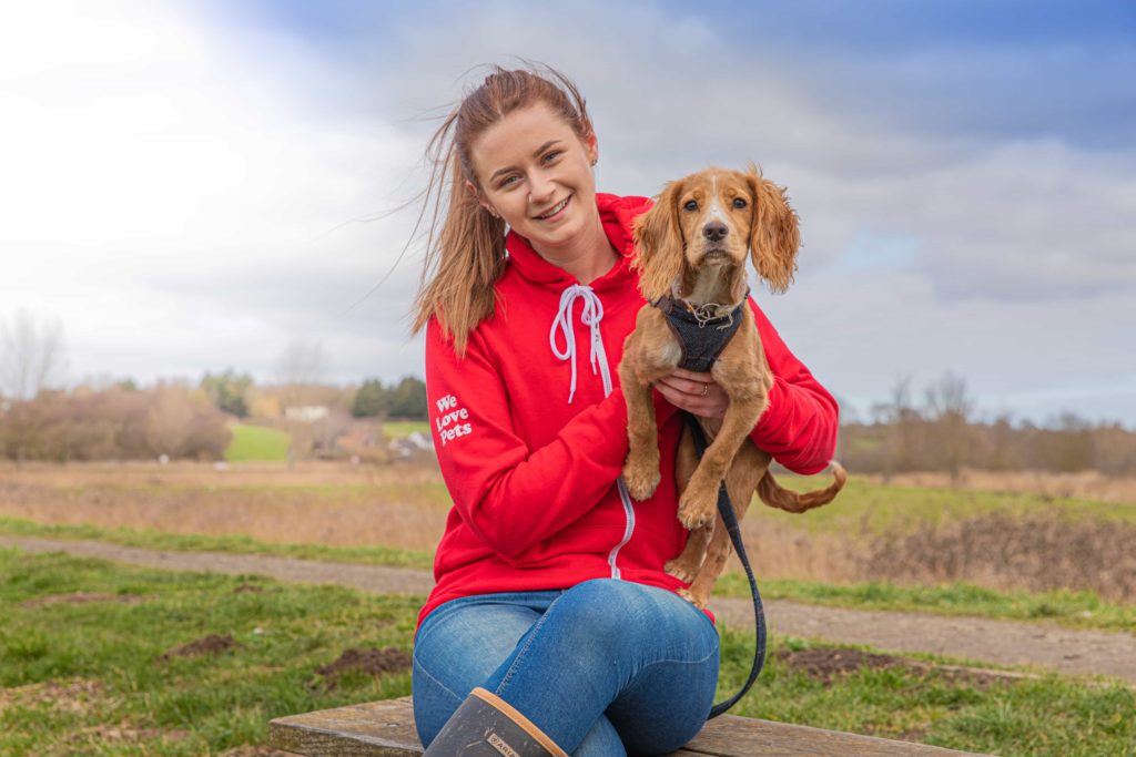 Louise Perez from We Love Pets Epsom sitting holding a dog