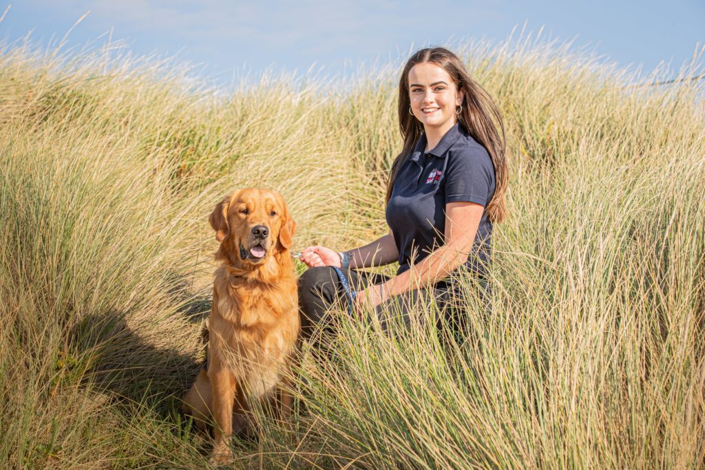 Sophie from We Love Pets Eastbourne hugging dog on a beach