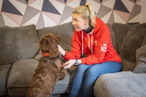 Professional pet sitter meeting a brown cocker spaniel in the dog's home before providing holiday pet care.