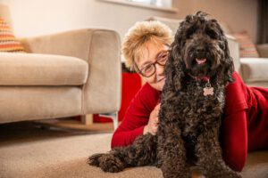Woman relaxing at home with her curly black dog, keeping Halloween pet safety in mind with a calm night in